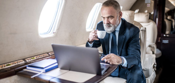 A passenger using a laptop in a business jet
