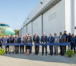 Group photo outside facility with aircraft in background