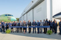 Group photo outside facility with aircraft in background