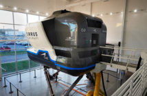 A simulator is sitting in a room with a lot of windows